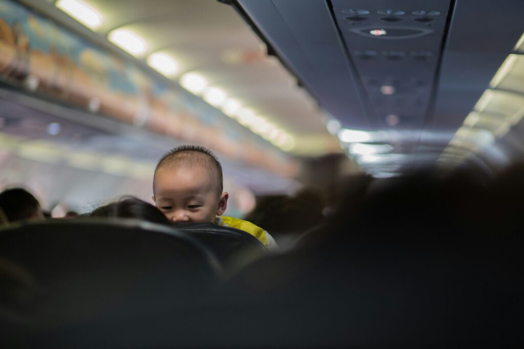 飛行機の座席であやされている子どもの画像
